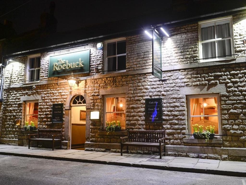 a building with benches in front of it at night at The Roebuck Inn in Chapel en le Frith