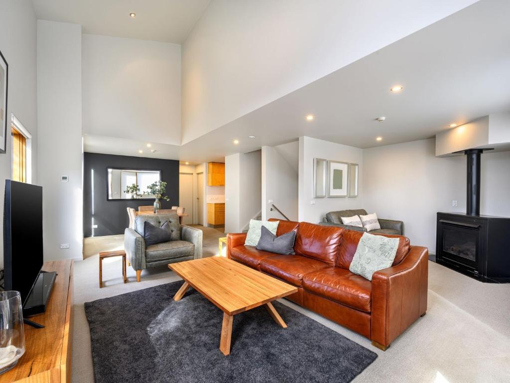 a living room with a leather couch and a table at Snow Stream 5 in Thredbo