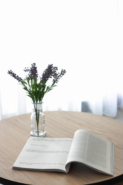 an open book on a table with a vase of flowers at The Euphoria Club Luxury Villas in Pefkochori