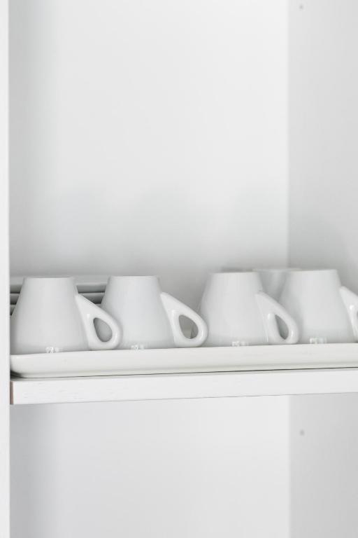 a shelf with four white cups and bowls on it at The Euphoria Club Luxury Villas in Pefkochori
