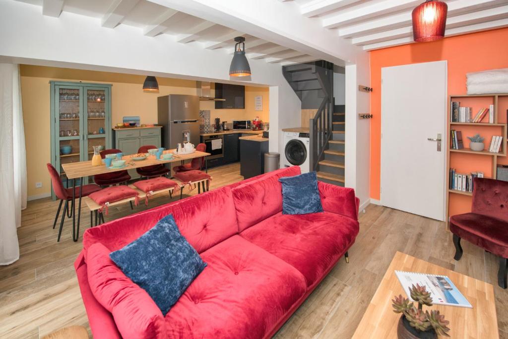 a living room with a red couch and a kitchen at L’Ancre des falaises - MAISON VUE MER & À 50M PLAGE (hypercentre) in Étretat