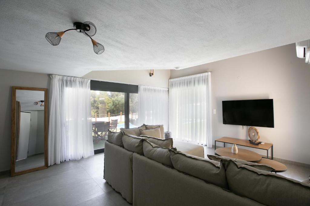 a living room with a couch and a flat screen tv at The Euphoria Club Luxury Villas in Pefkochori