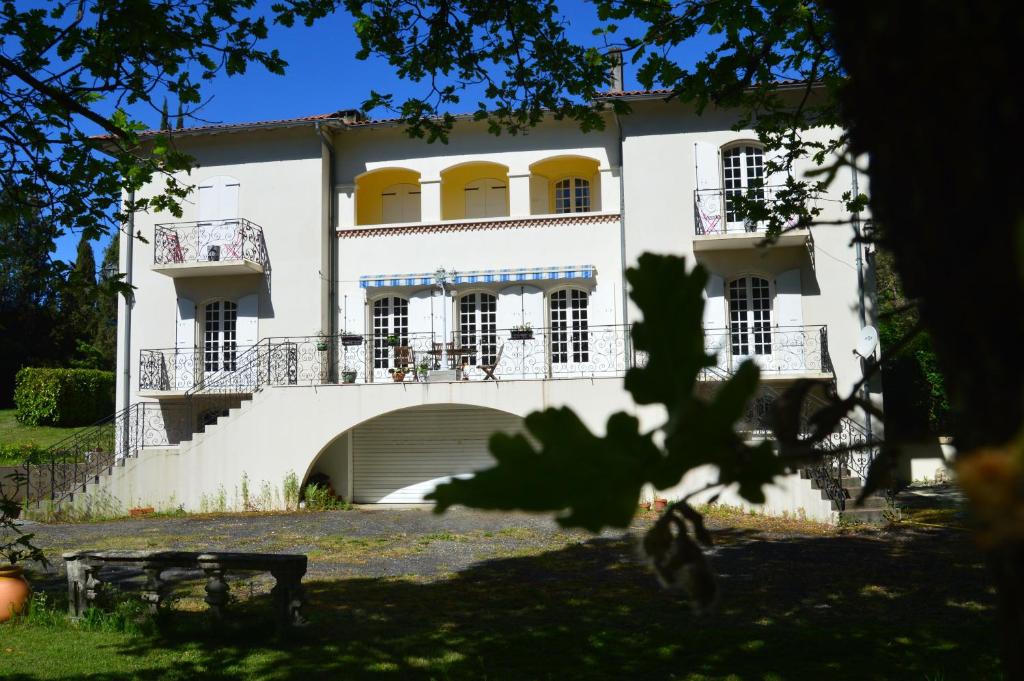 a white house with yellow windows and a balcony at L'Escalère in Arnaud-Guilhem