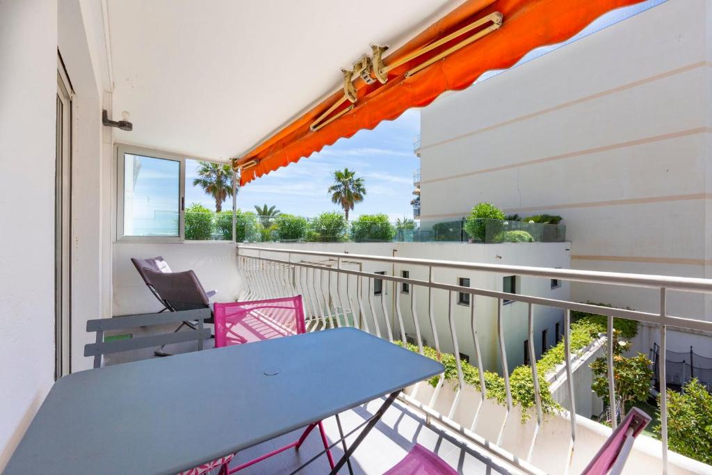 einen Balkon mit einem blauen Tisch und rosa Stühlen in der Unterkunft Modern apartment 2 bedrooms quiet terrace in a palm beach area, 30 meters from seaside in Cannes