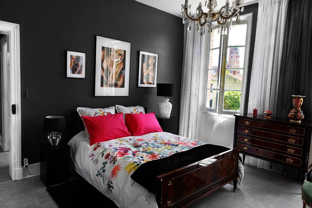 una camera da letto con un letto con cuscini rossi e una finestra di LE CHERCHE MIDI Chambres d'hôtes avec CUISINE EQUIPEE grand jardin PARKING SECURISE GRATUIT ad Albi