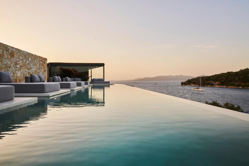 una piscina a sfioro con sedie e vista sull'acqua di Azur Retreat a Meganisi