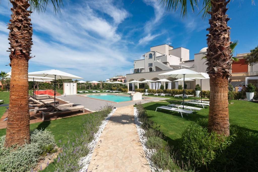 a resort with a swimming pool and palm trees at Insula Boutique Hotel in Procida