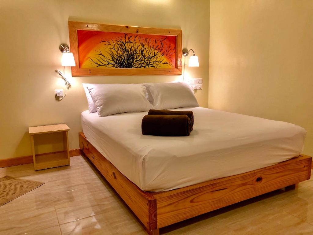 a bedroom with a large bed with a painting on the wall at Royal Reef Stay in Mathiveri