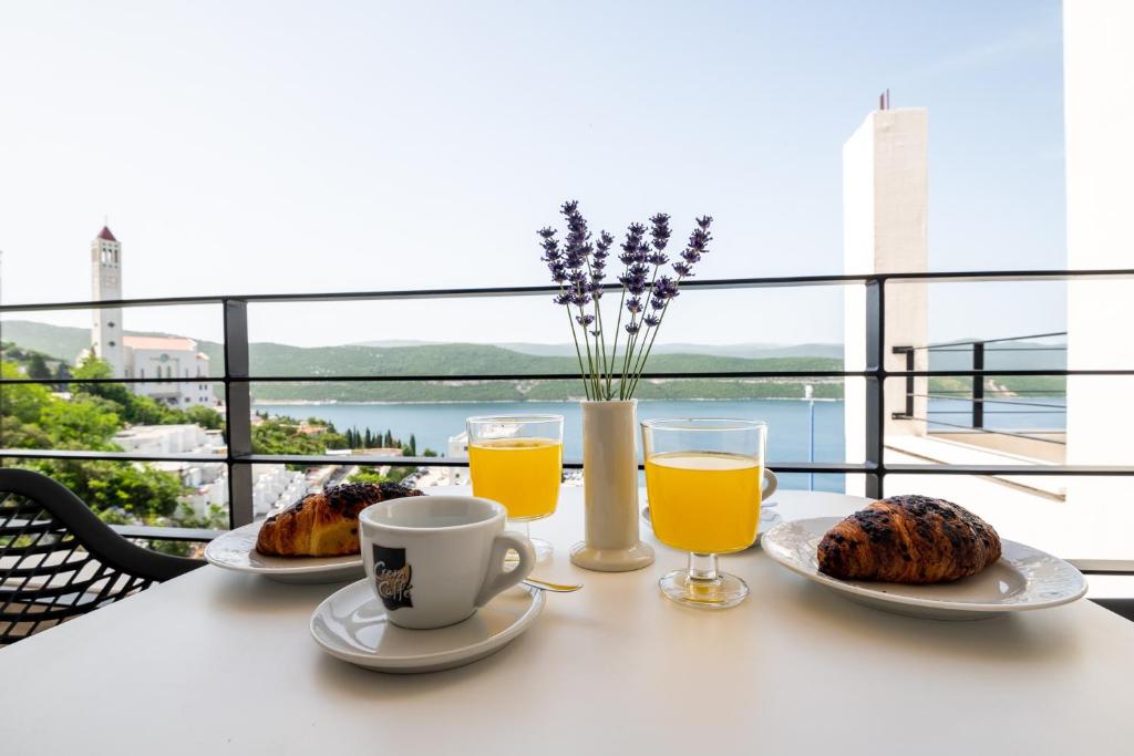 a table with two plates of food and two glasses of orange juice at Villa Catalpa in Neum