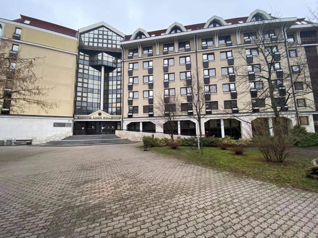 een groot gebouw met een stenen oprit ervoor bij KLK Hotel in Debrecen