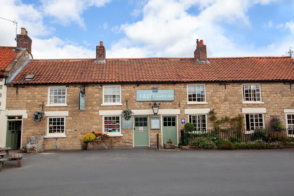 un gran edificio de ladrillo con un cartel. en The Fox and Hounds Country Inn, en Pickering