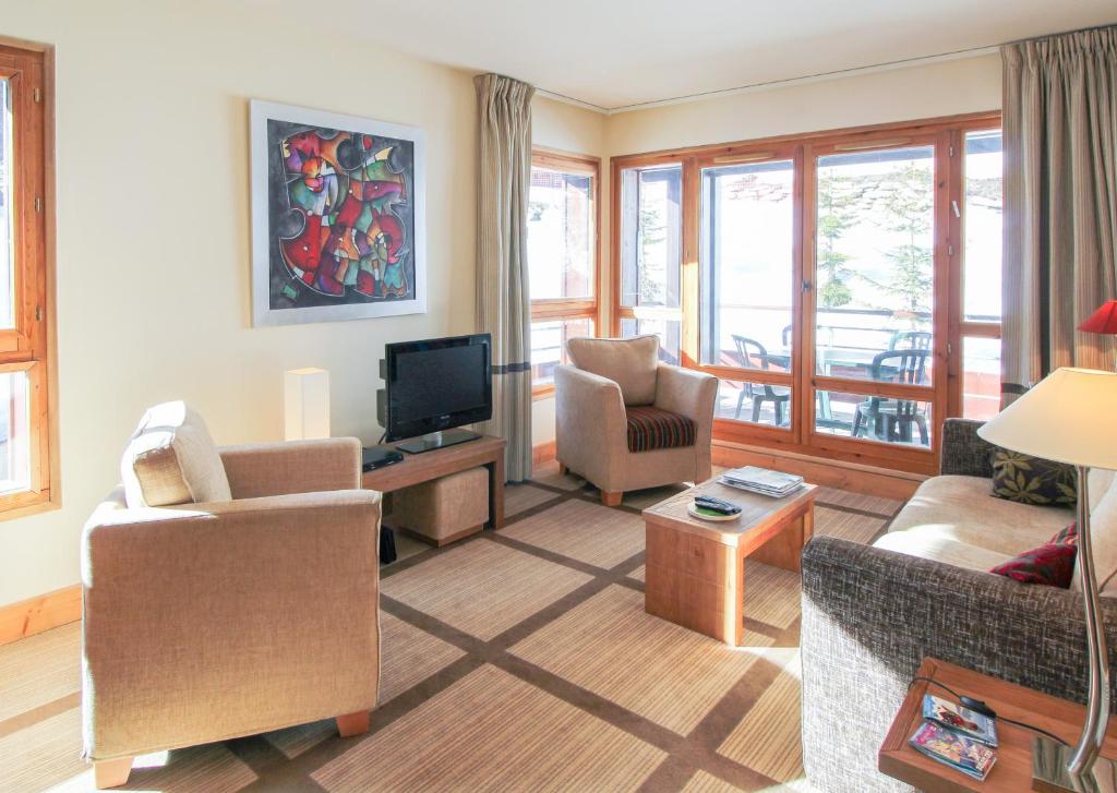 a living room with a couch and chairs and a tv at Spacious Family 2-bed, 2-bath with parking, private piste in Flaine