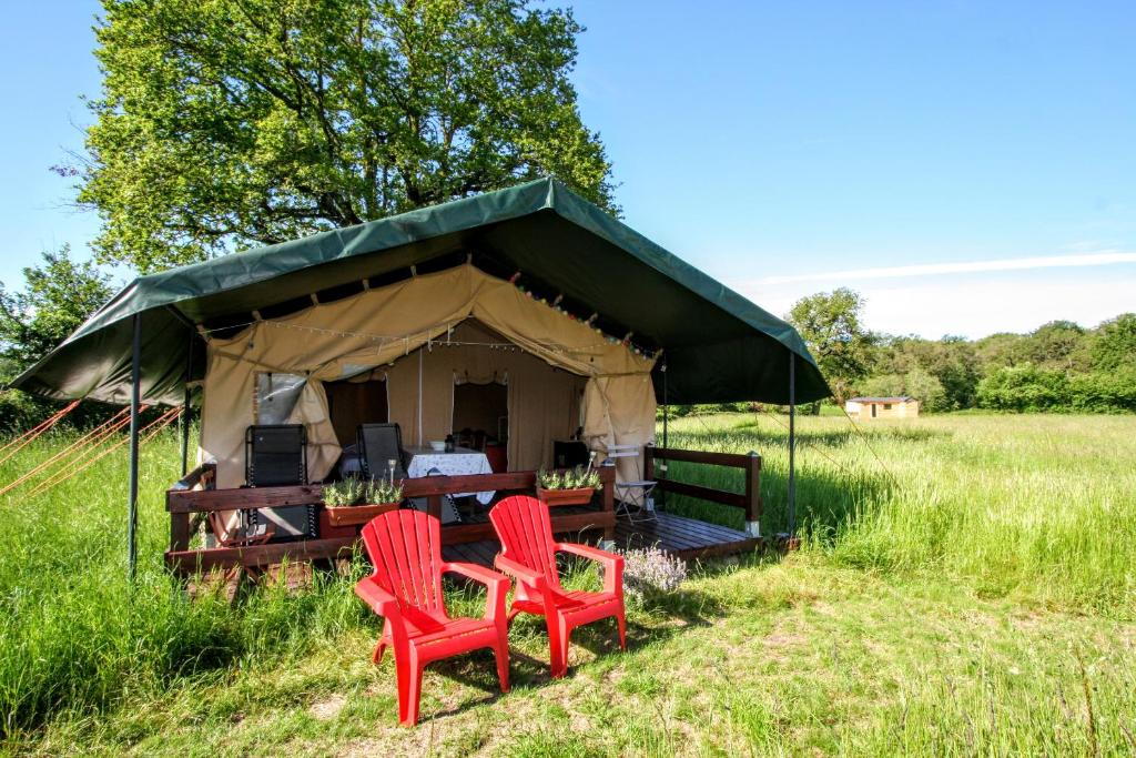 2 chaises rouges et une table dans une tente dans l'établissement Safaritent Les Pourettes, à Feusines