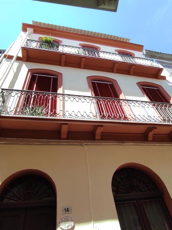 イグレージアスにあるCasa Colombiniの赤い窓とバルコニーが備わる白い建物