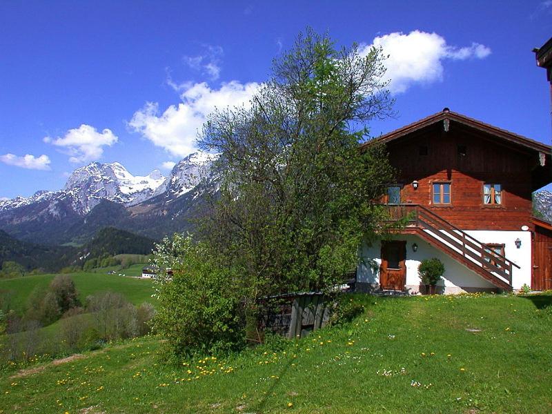 una casa en una colina con montañas en el fondo en Haus Unterwegscheid Ferienwohnungen, en Ramsau