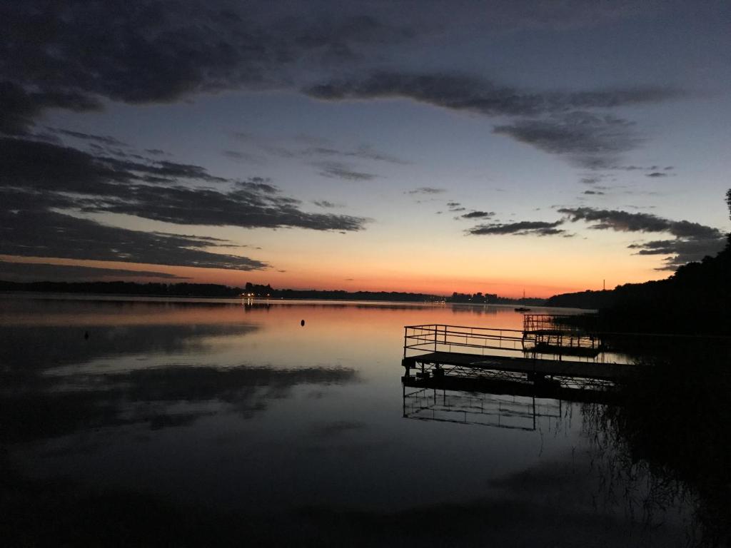 a sunset on a lake with a dock at Domek Shrek in Boszkowo