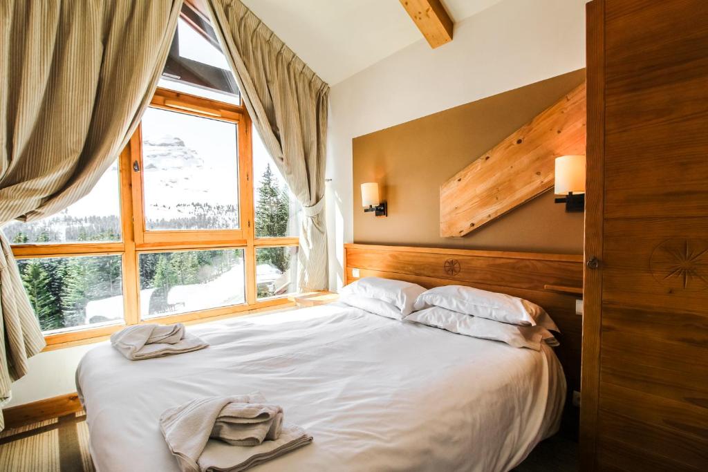 Schlafzimmer mit einem großen Bett und einem Fenster in der Unterkunft Cosy, modern 2-bed with fireplace & beautiful views in Flaine