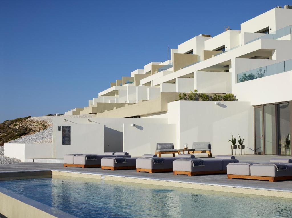 a villa with a swimming pool in front of a building at Domes White Coast Milos, Adults Only - Small Luxury Hotels of the World in Mytakas
