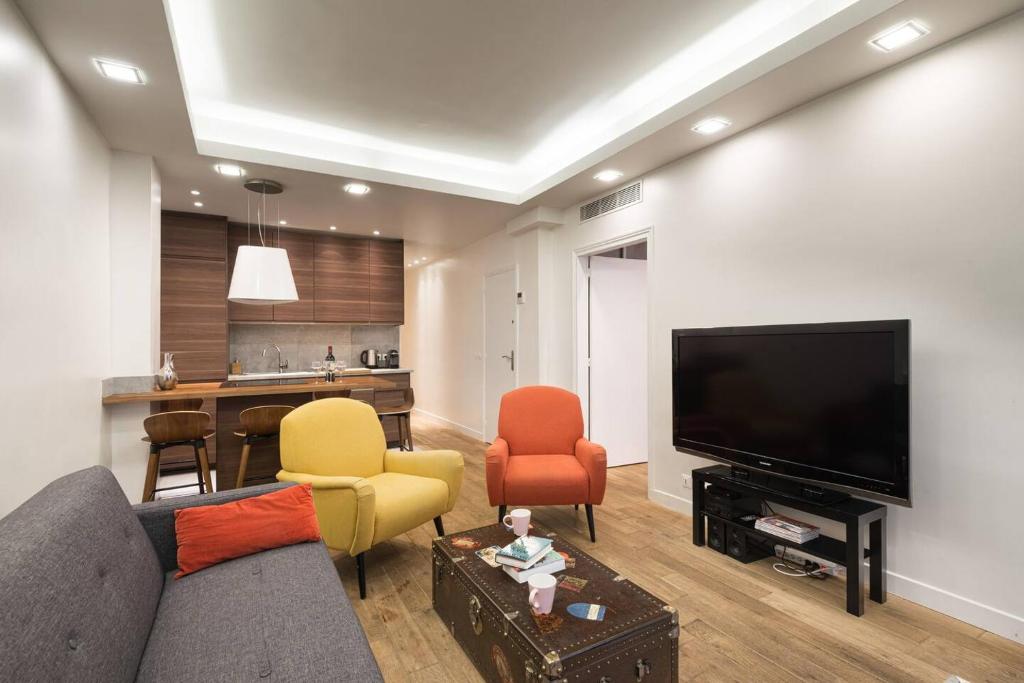 a living room with a couch and chairs and a television at 3 double bedrooms apartment in Montmartre near subway AC in Paris