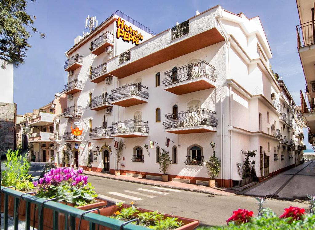 een wit gebouw met balkons in een straat bij Hotel da Peppe in Letojanni