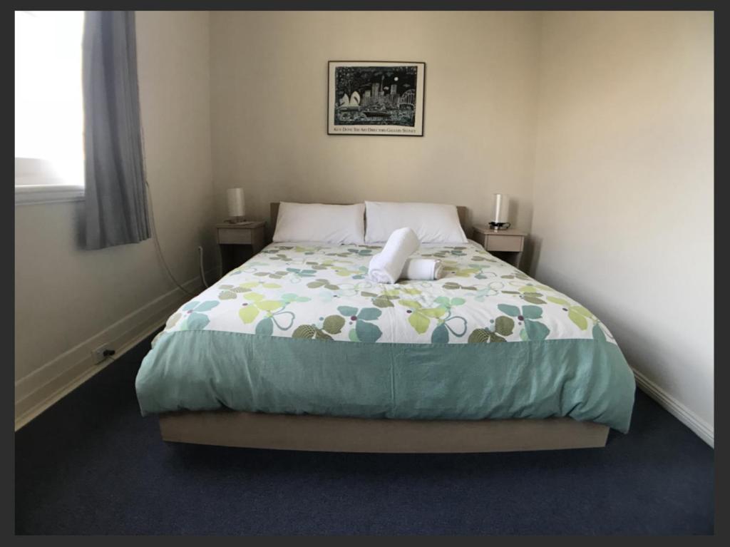 a bedroom with a bed with a green and yellow comforter at Malvern Backpackers in Melbourne