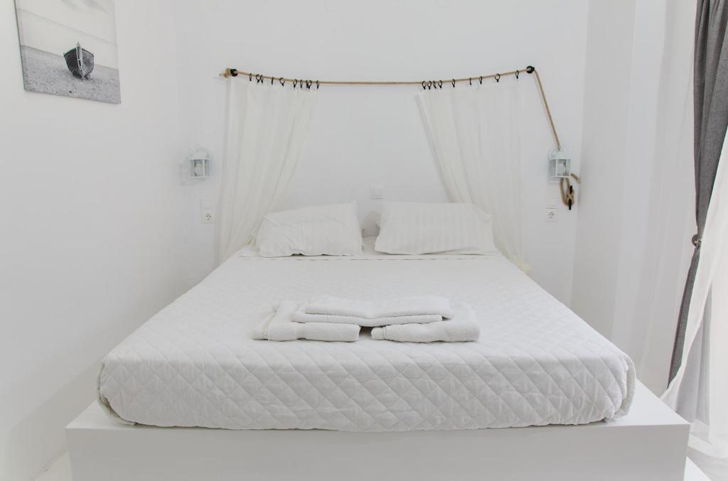 a white bed with two towels on top of it at Golden Star Praxitelous in Agia Marina Aegina