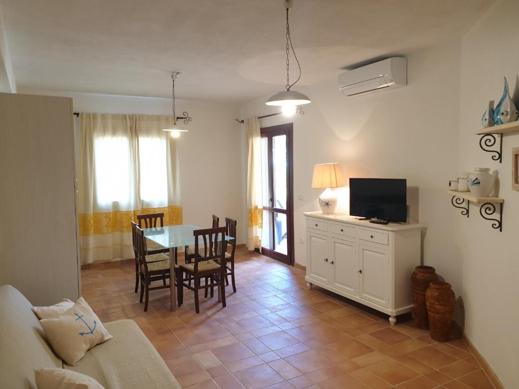 a living room with a table and chairs and a couch at Capo Figari 9, appartamento a Golfo Aranci in Golfo Aranci