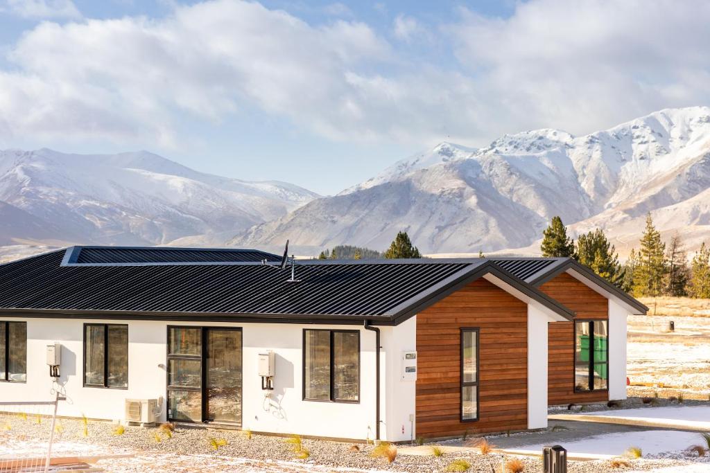a house with a solar roof and mountains in the background at Tekapo Space Apartment in Lake Tekapo