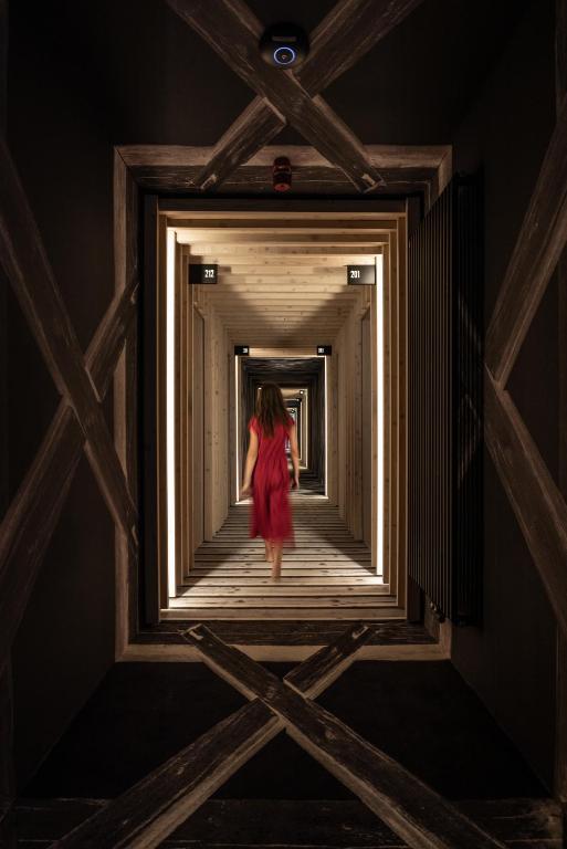 a woman in a red dress walking down a corridor at Hotel Bohinj in Bohinj