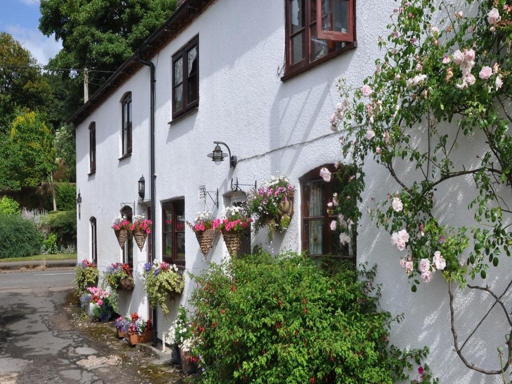 a white building with flower baskets on it at Shepherds Row Bed and Breakfast in West Haddon