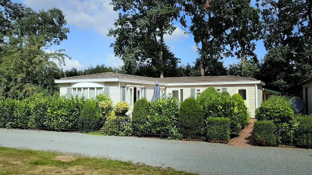 una casa bianca con una recinzione di fronte di Chalet 42 'Vuursteenberg' Bospark IJsselheide Zwolle Hattemerbroek a Hattemerbroek