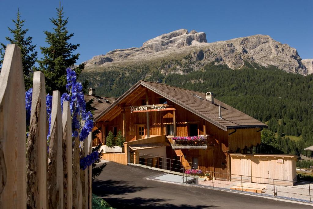 un bâtiment en bois avec une montagne en arrière-plan dans l'établissement Pension Angelo, à Corvara in Badia