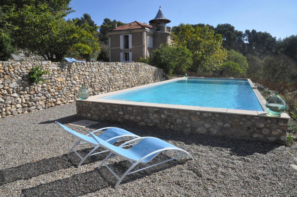 een stoel en een zwembad met een huis bij Pavillon de Beauregard in Aix-en-Provence