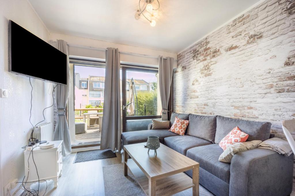 un salon avec un canapé et un mur de briques dans l'établissement Galene, à Courseulles-sur-Mer