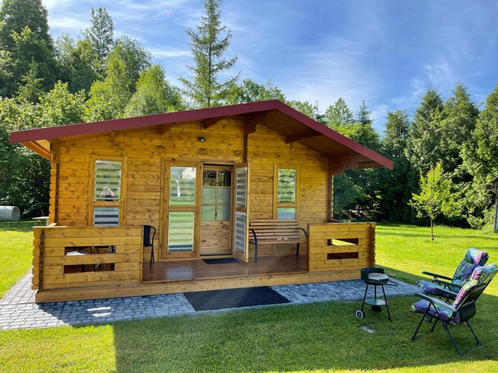 une cabane en rondins avec une terrasse couverte et une chaise dans l'établissement Domek nad Solina z klimatyzacją, à Uherce Mineralne