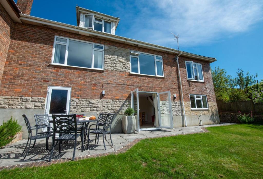 a brick house with chairs and a table in the yard at Avocet House in West Lulworth