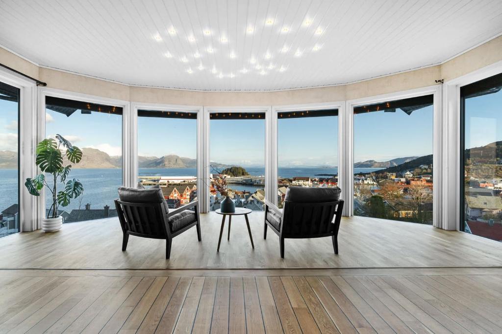 a living room with two chairs and a table and large windows at Utsikten in Kalvåg
