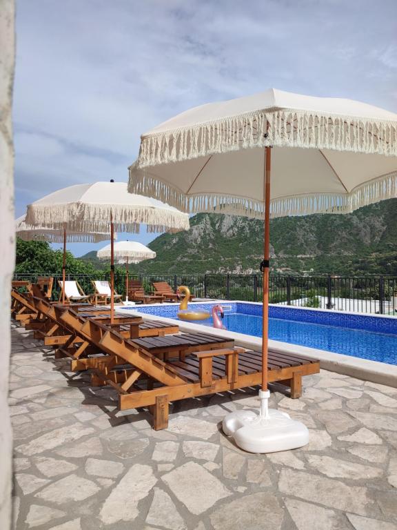 a row of tables and umbrellas next to a swimming pool at Apartments Kingfisher in Virpazar