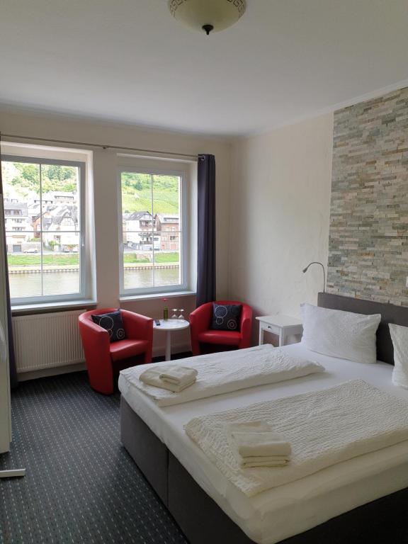 una camera d'albergo con un letto e due sedie rosse di Haus Burgfrieden Cochem a Cochem
