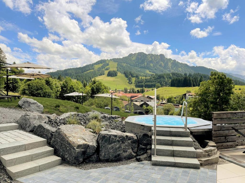 una piscina en un jardín de rocas con una montaña en Berghoteltirol, en Jungholz