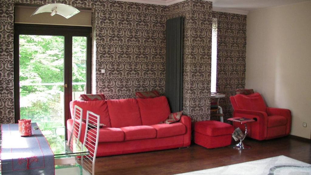 un soggiorno con un divano rosso e 2 sedie di Premium Apartment a Wisła