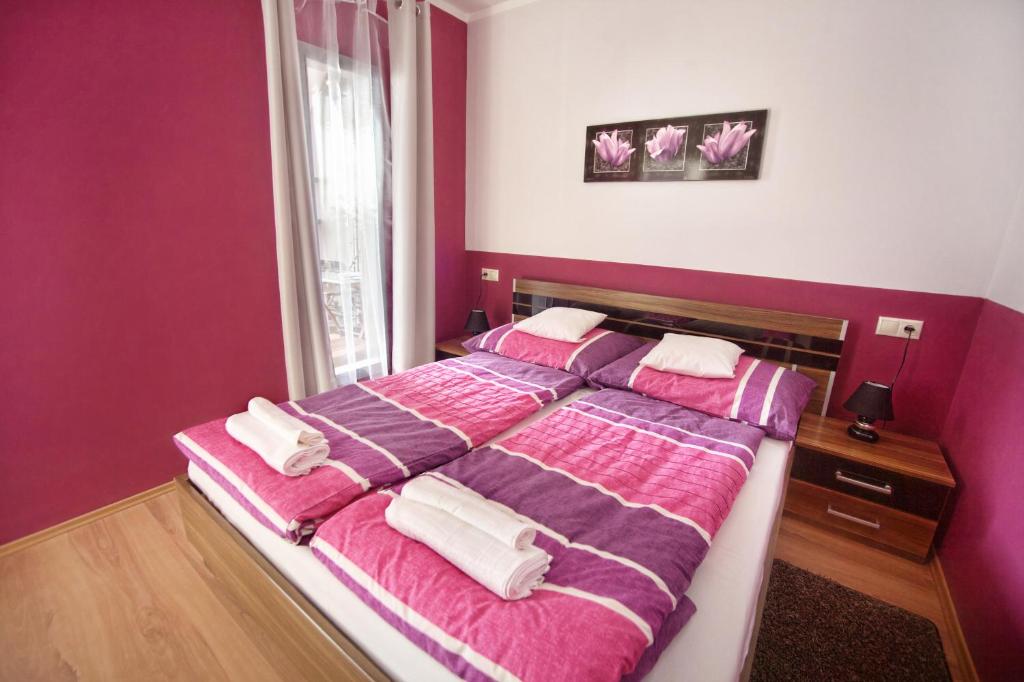 シャールヴァールにあるCecília Apartmanのベッドルーム1室(ピンクと紫のシーツが入った大型ベッド1台付)