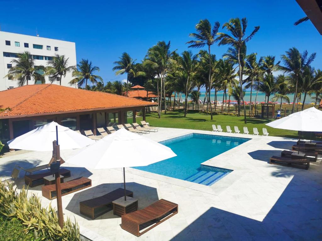 a pool at the resort with umbrellas and chairs at Casa Mia Pousada in Cabedelo