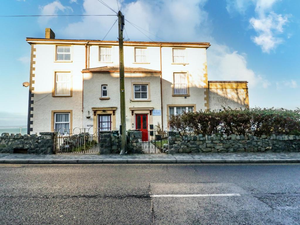 a white house on the side of a street at Llys Madoc, Basement Apartment in Penmaen-mawr