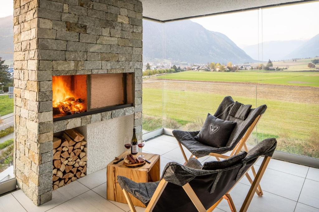 einen Kamin im Wohnzimmer mit 2 Stühlen in der Unterkunft Bellevue Bruneck - Suites & Lofts in Bruneck