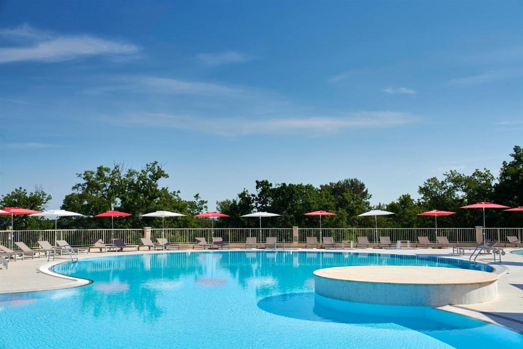 a large swimming pool with chairs and umbrellas at Apartments Bellevue Plava Laguna in Poreč