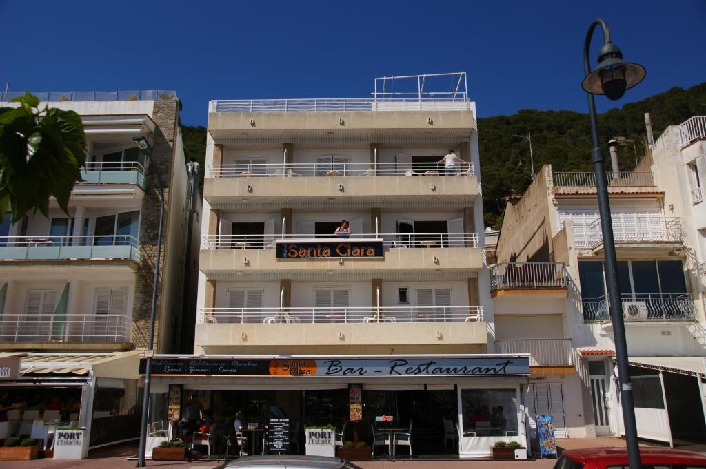 a tall white building with people on the balcony at Hostal Santa Clara in L'Estartit
