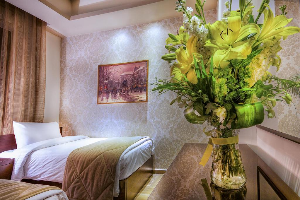 Zimmer mit einem Bett und einer Vase gelber Blumen in der Unterkunft Nadine Hotel Suites in Amman