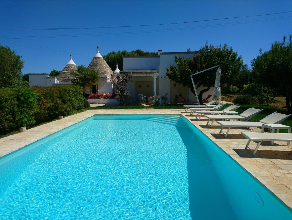 a swimming pool with chairs and a house at Trulli La Pietraia in Ostuni