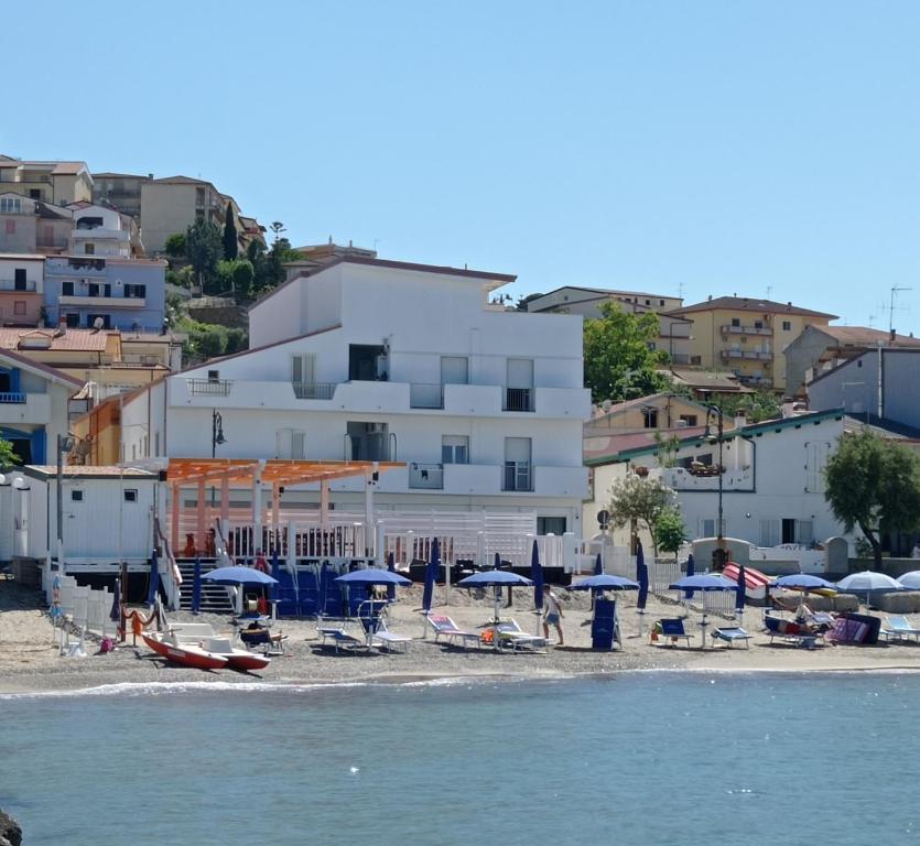 ein Strand mit blauen Sonnenschirmen, Stühlen und Menschen in der Unterkunft B&B Gattopardo in Cariati